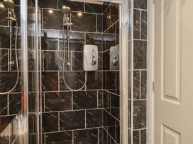 A bathroom with a shower and grey tiles at 11 Rutland Street in Filey
