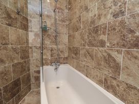 A bathtub with a shower and wall tiles at 11 Rutland Street Filey