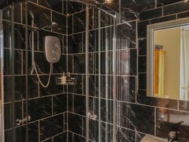 A shower with black tiles and a soap dispenser at 11 Rutland Street, Filey
