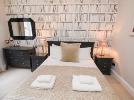 A bedroom with a bed and a wall designed to look like a bookshelf at All Seasons in Filey