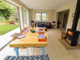 A dining area with wooden table set with blue plates and glassware next to a living space with a blue sofa and a wood burning stove at Natterjacks in Syderstone