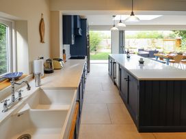 A kitchen with blue cabinets a white countertop a sink a toaster and an island with pendant lights at Natterjacks in Syderstone
