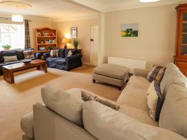 A living room with sofas a wooden coffee table a bookshelf and a cabinet at Natterjacks in Syderstone