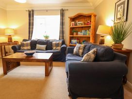 A living room with two blue sofas a wooden coffee table and bookshelf at Natterjacks in Syderstone