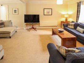 A living room with sofas a wooden coffee table a tv on a round stand and a lamp at Natterjacks in Syderstone