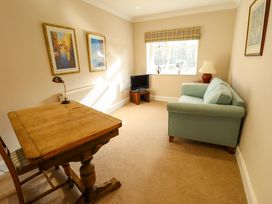 A small room with a wooden table and chair a green sofa a small television and framed pictures at Natterjacks in Syderstone