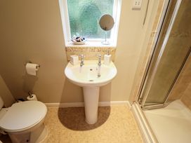 A bathroom with a toilet a pedestal sink with accessories and a shower cubicle at Natterjacks in Syderstone