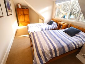 A bedroom with two single beds striped bedding a wooden wardrobe and a bedside table with a lamp at Natterjacks in Syderstone