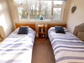 A bedroom with two single beds and a bedside table with a lamp at Natterjacks in Syderstone
