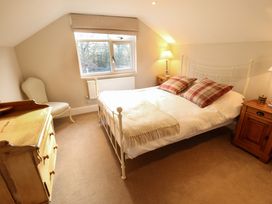 A bedroom with a bed with checkered pillows two bedside tables with lamps a wooden chest of drawers and an upholstered chair at Natterjacks in Syderstone