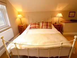 A bedroom with a metal frame bed two plaid pillows bedside tables with lamps and a window at Natterjacks in Syderstone