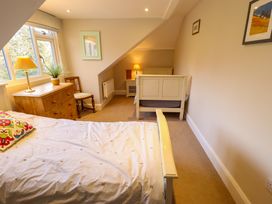 A bedroom with two beds a wooden dresser and a chair by a window at Natterjacks in Syderstone