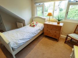 A bedroom with a single bed a wooden chest of drawers a table lamp a plant and a chair at Natterjacks in Syderstone