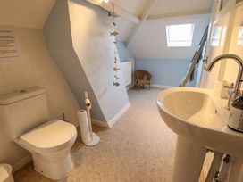 A bathroom with a toilet a sink a wicker chair and a skylight window at Natterjacks in Syderstone
