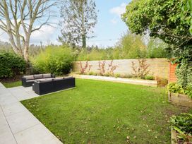 A garden with grass lawn a wooden fence outdoor sofa set and plants at Natterjacks in Syderstone