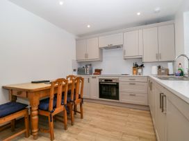 A kitchen with cabinets, oven, sink, and dining table at Capella Cottage in Keswick