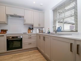 A kitchen with cabinets, oven, sink, and utensils at Capella Cottage in Keswick