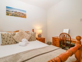 A bedroom with a bed, nightstand, chair, and a photograph at Capella Cottage in Keswick