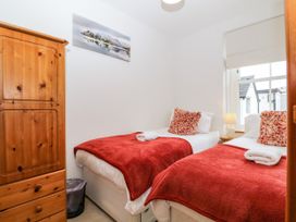 A bedroom with two beds and a wardrobe at Capella Cottage in Keswick