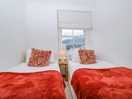 A bedroom with two beds and a lamp at Capella Cottage in Keswick
