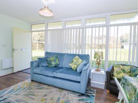 A living room with a blue sofa and patterned cushions near a window with vertical blinds at Number 19 in Cromer