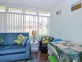 A sitting area with blue sofa and black chair with leaf patterned cushions next to a table with leaf patterned tablecloth at Number 19 in Cromer