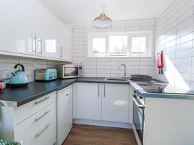 A kitchen with white cabinets black countertops a kettle toaster microwave oven and a window at Number 19 in Cromer