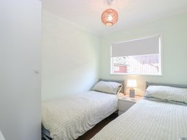 A bedroom with two single beds a nightstand with a lamp and a window with a blind at Number 19 in Cromer