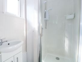 A bathroom with a white sink cabinet and a glass door shower at Number 19 in Cromer