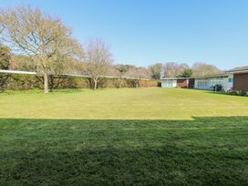 A grassy lawn with several leafless trees and modern single-story buildings at Number 19 in Cromer
