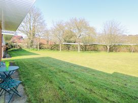 A large grassy garden with scattered trees and a small table with two chairs near a building at Number 19 in Cromer