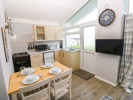 A kitchen with a dining table set for four a stove microwave and sink at Chalet 27 in Port Eynon