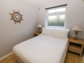 A bedroom with a double bed white bedding bedside tables with lamps and a window at Chalet 27 in Port Eynon