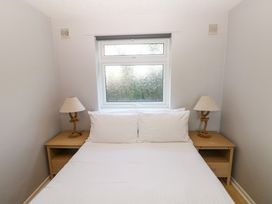 A bedroom with a double bed two pillows two bedside tables and two lamps under a window at Chalet 27 in Port Eynon