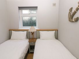 A bedroom with two single beds a bedside table with a lamp and a window above the beds at Chalet 27 in Port Eynon