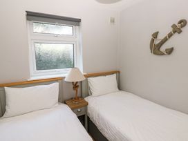 A bedroom with two single beds a window a bedside table with a lamp and an anchor decoration on the wall at Chalet 27 in Port Eynon