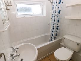 A bathroom with a bathtub a shower with a blue turtle curtain a sink and a toilet at Chalet 27 in Port Eynon