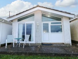 The exterior of a single-storey property with a small patio area with two chairs and a table at Chalet 27 in Port Eynon