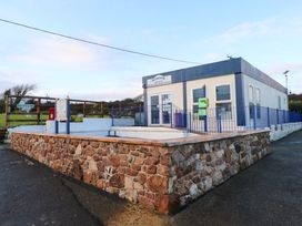 A reception office building with a stone wall and blue railings at Newpark Holiday Park in Port Eynon