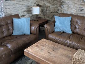 A living room with sofas and a wooden table at La Bastille in Maenclochog