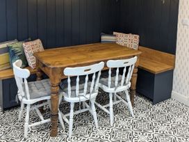A dining room with a wooden table and white chairs at La Bastille in Maenclochog