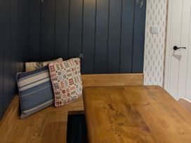 A dining area with a wooden table and cushions at La Bastille in Maenclochog
