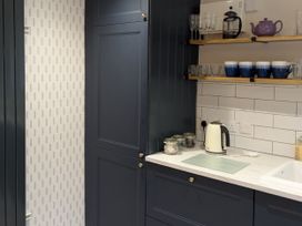 A kitchen with cabinets and shelves displaying teapot and glasses at La Bastille in Maenclochog