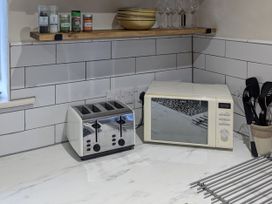 A kitchen with a toaster and microwave on the counter at La Bastille in Maenclochog