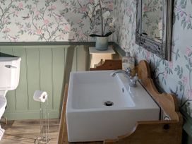 A bathroom with a sink, toilet and floral wallpaper at La Bastille in Maenclochog
