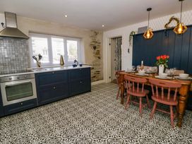 A kitchen with cabinets, a dining table and chairs at La Bastille in Maenclochog
