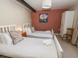 A bedroom with two beds, a painting on the wall, and a wardrobe at La Bastille in Maenclochog
