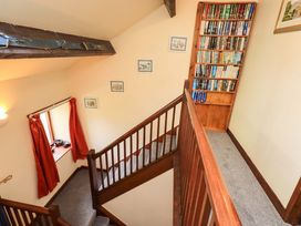 A staircase with a bookshelf and window at Tethera Cottage Bampton, Cumbria