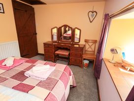 A bedroom with a bed and dressing table at Tethera Cottage in Bampton, Cumbria