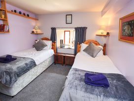 A bedroom with twin beds and a window at Tethera Cottage in Bampton, Cumbria